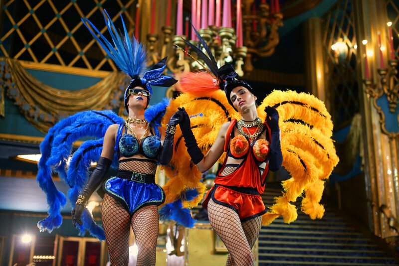 Two women in fishnets, feathers and headdresses strut on stage in Fashion Freak Show by Jean Paul Gaultier