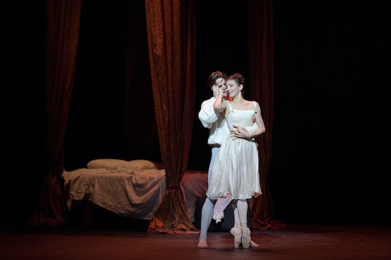 A man embraces a ballerina en pointe on stage