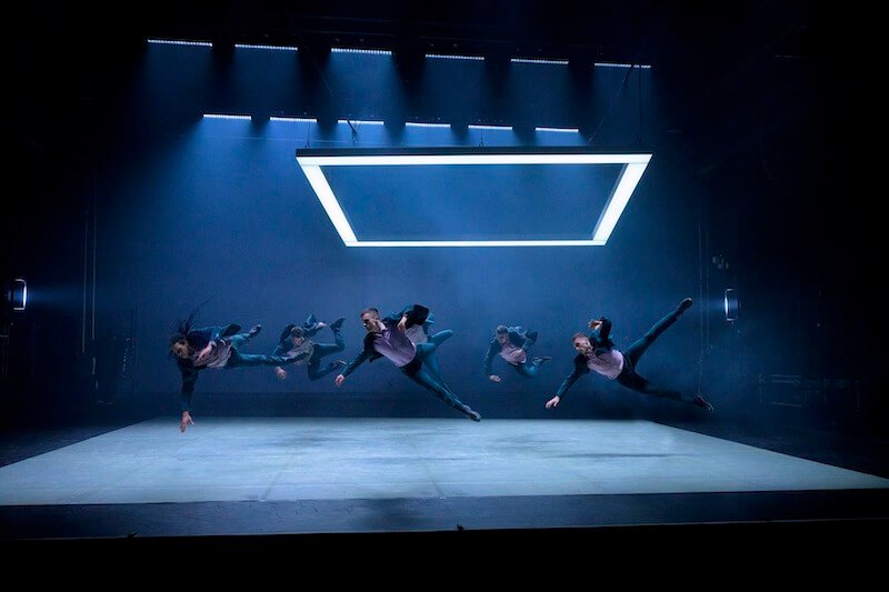 A group of male dancers jumps on stage