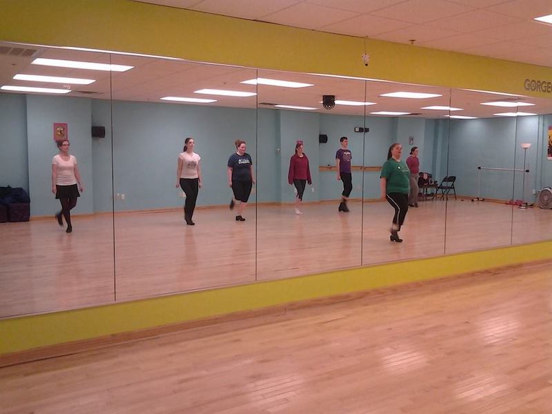 Women learning Irish dance stand in front of a mirror