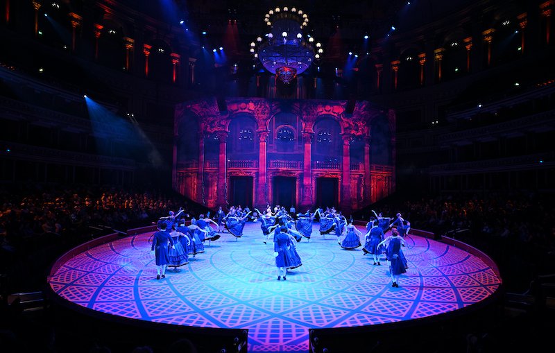 Pairs of dancers stand on stage in black