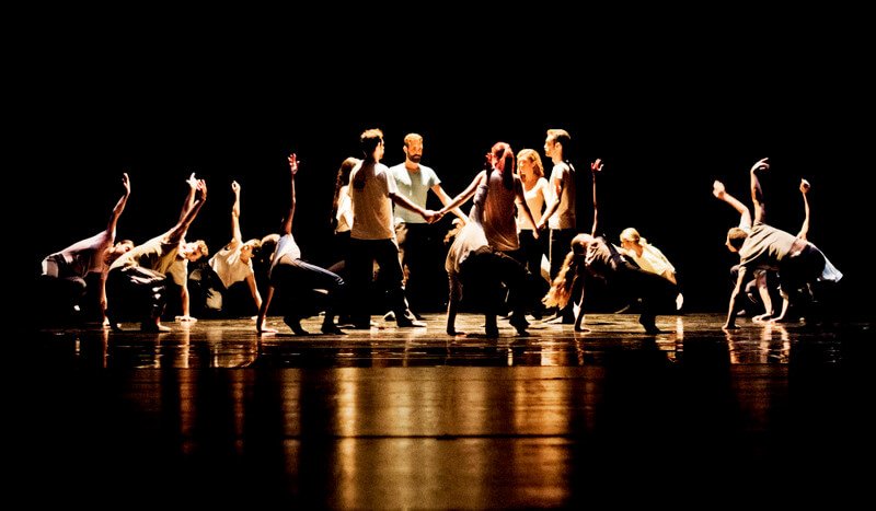 Dancers hold hands, facing each other in a circle 