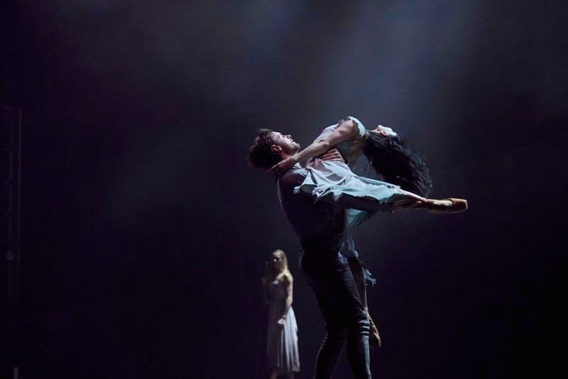 A man lifts a woman who arches backward on stage