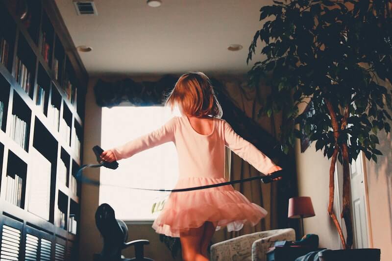 A young girl in pink twirls in her living room