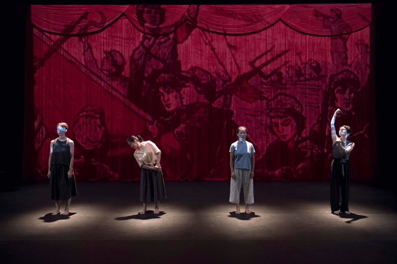 Four women stand in front of cartoon projection in Wen Hui's RED